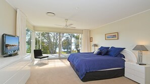 Relax in this serene bedroom with a large bed, flat-screen TV, and comfortable chair.