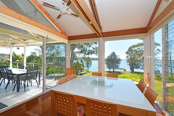 A spacious dining area with a large table and chairs, overlooking a lake.