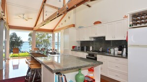 Une cuisine moderne dotée d’un grand îlot central, de meubles blancs et offrant une vue sur l’extérieur.