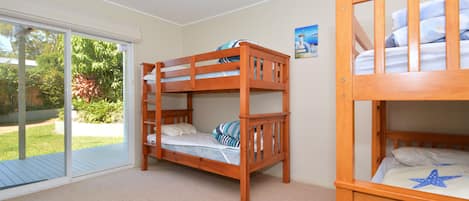 A room with two bunk beds, a sliding glass door leading to a balcony, and a small painting on the wall.