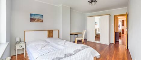A bedroom with a bed, bedside table, chair, and a desk with a chair.