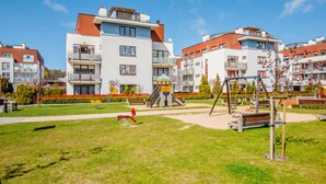 Ein Spielplatz mit Schaukeln und Rutsche, umgeben von Wohngebäuden.