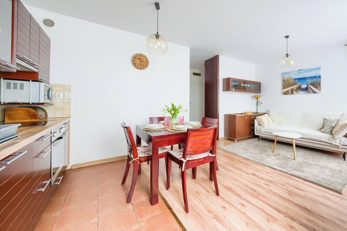 A modern kitchen with wooden cabinets and a dining area with a wooden table and chairs.