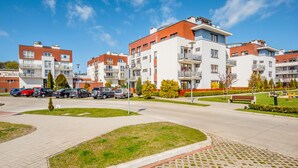 Ein moderner Apartmentkomplex mit mehreren Gebäuden, einem Parkplatz und gepflegter Bepflanzung.