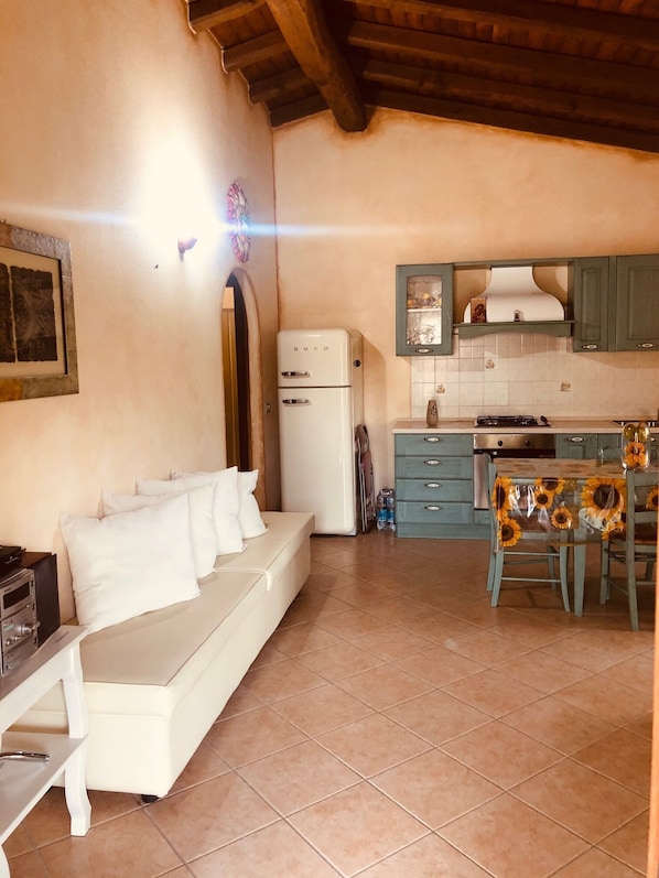 A compact living space with a sofa, kitchenette, and tiled floor.