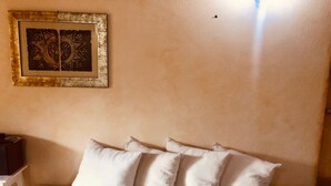 A beige sofa with four white cushions against a plain wall with a framed artwork above it. - Fantastico San Teodoro STRAU02 (San Teodoro)