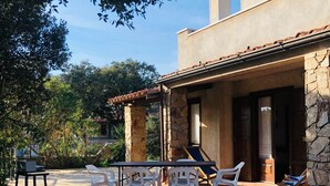 A patio with a table and chairs, a stone wall, and a building with a tiled roof.