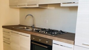 A modern kitchen with white cabinetry, a stainless steel sink, a gas stove, and a built-in oven.