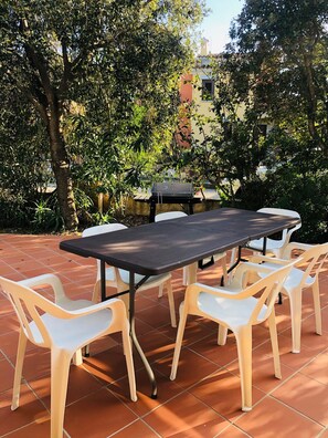 An outdoor patio with a rectangular table and six white plastic chairs. - Fantastico San Teodoro Fraili LUC01 (San Teodoro)