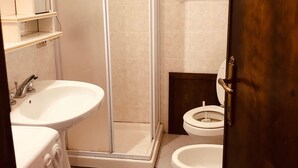 A bathroom with a shower, two sinks, a toilet, and a mirror.