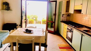 A kitchen with a dining table, chairs, a stove, and cabinets.