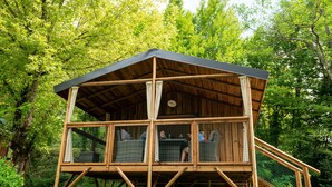 A wooden cabin with a balcony, surrounded by trees. - Camping Collonges-la-Rouge (Collonges-la-Rouge)