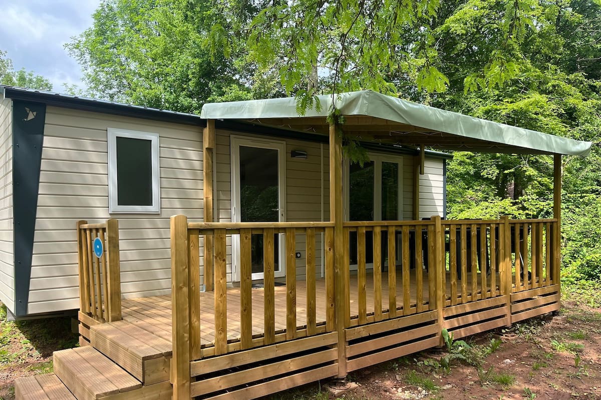 A wooden deck with a covered porch and a small attached building.