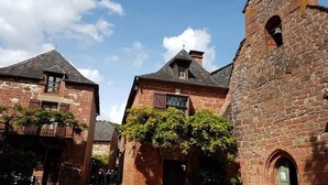 A narrow cobblestone street flanked by historic stone buildings with steep roofs and a bell tower. - Camping Collonges-la-Rouge (Collonges-la-Rouge)