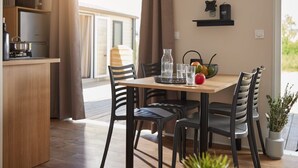 A modern kitchen with a wooden table and chairs, a stove, and a hanging pot rack. - Camping Collonges-la-Rouge (Collonges-la-Rouge)