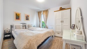 A bedroom with a bed, a nightstand, a dresser, a mirror, and two framed pictures on the wall. - Apartamenty Sun & Snow Na Solnej (Kolobrzeg)