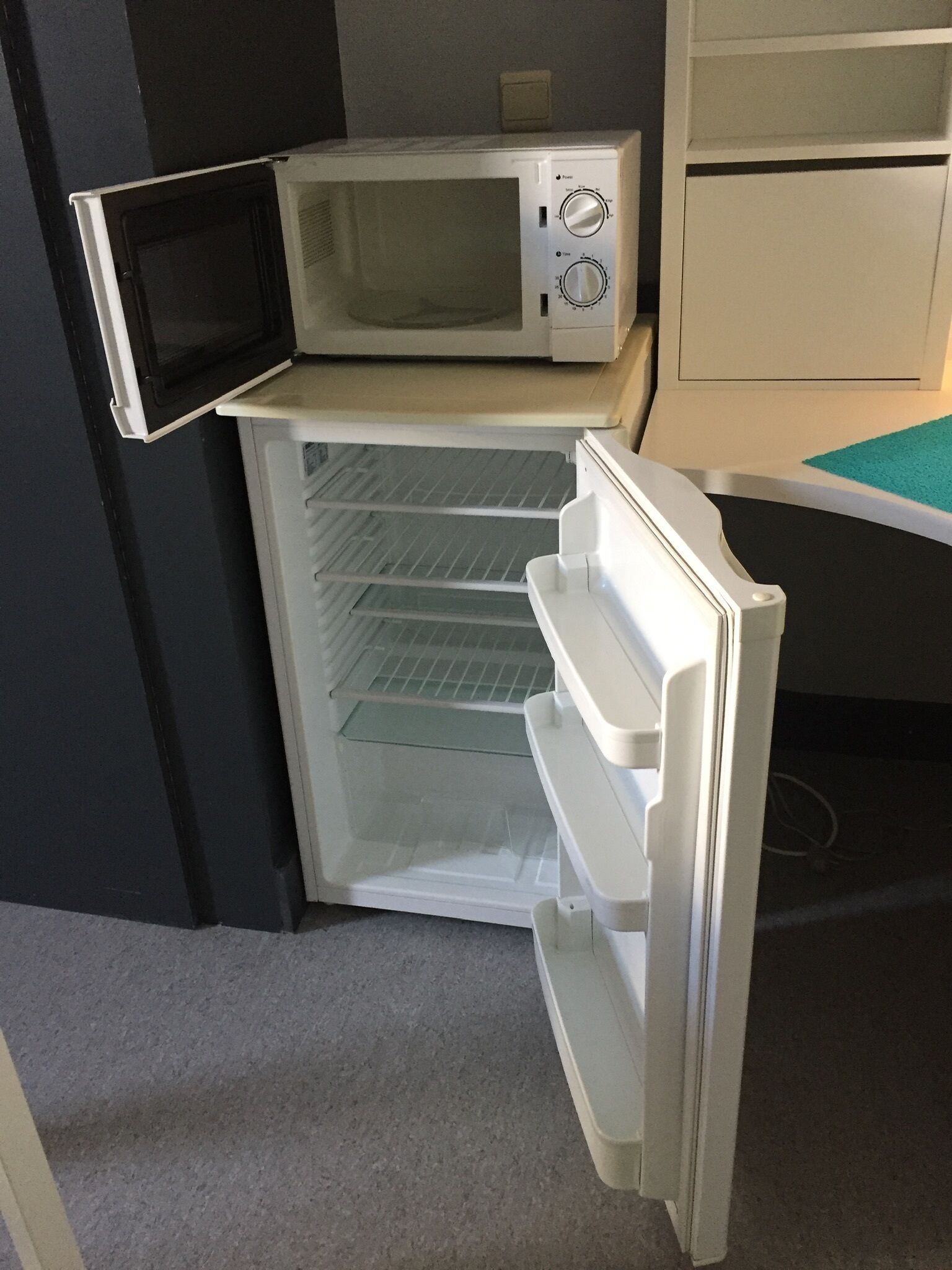 Ein kompakter Kühlschrank mit integriertem Mikrowellenherd, einem separaten Gefrierfach und einer kleinen Ablage.
