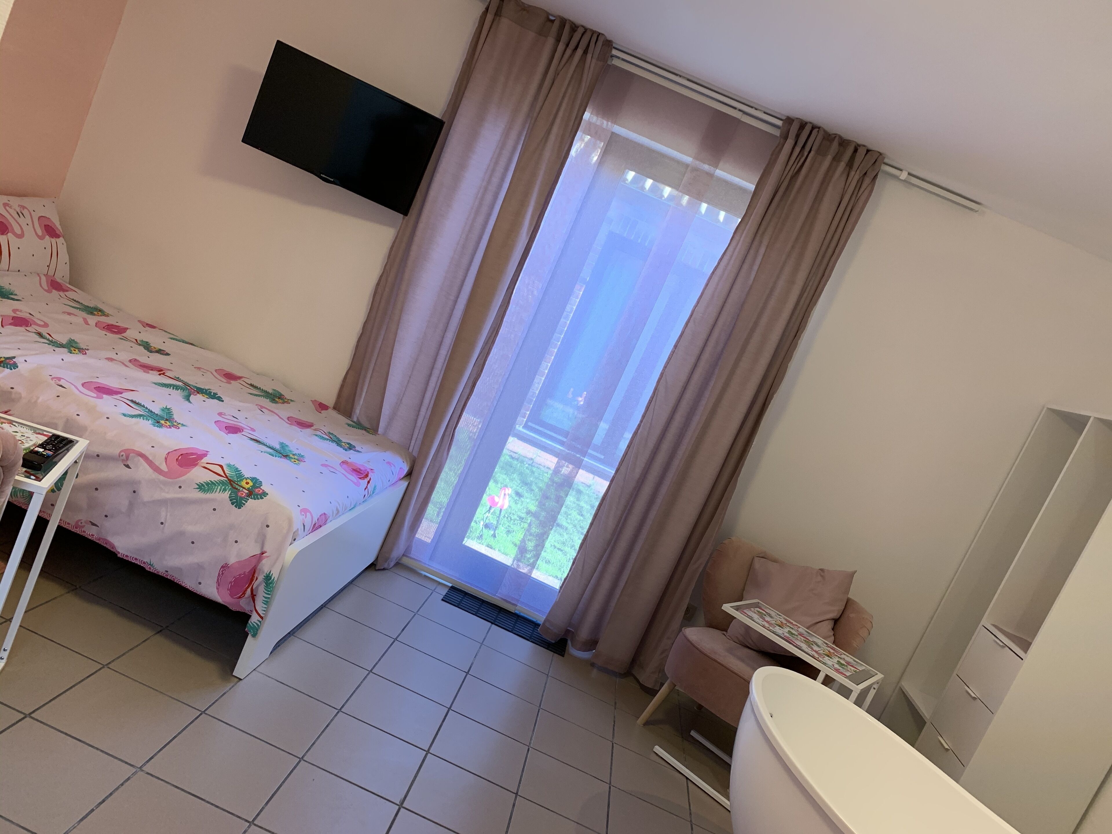 Habitación de hotel con cama, escritorio, silla, baño y televisor en la pared.