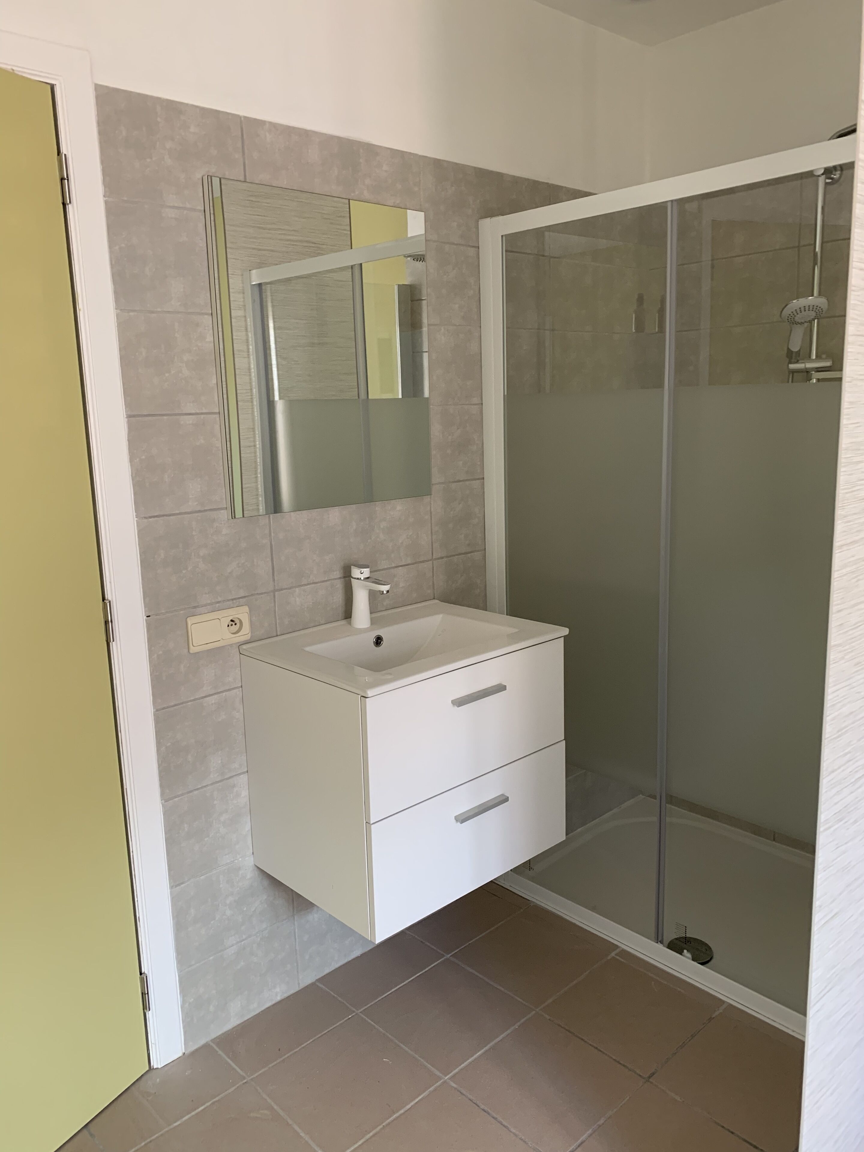 Un baño con tocador blanco, espejo y cabina de ducha de vidrio.