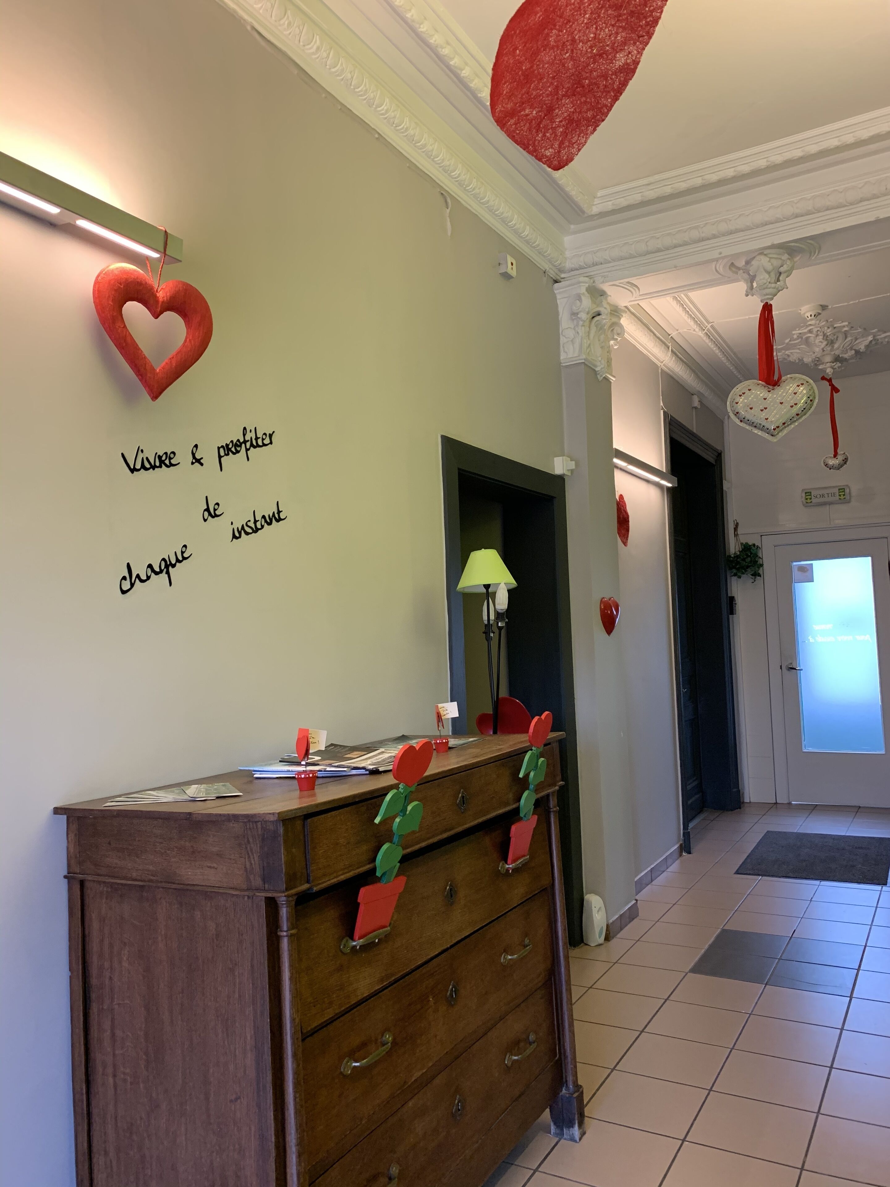Un espace d’accueil d’hôtel avec un comptoir en bois, un miroir et des décorations en forme de cœur rouge.
