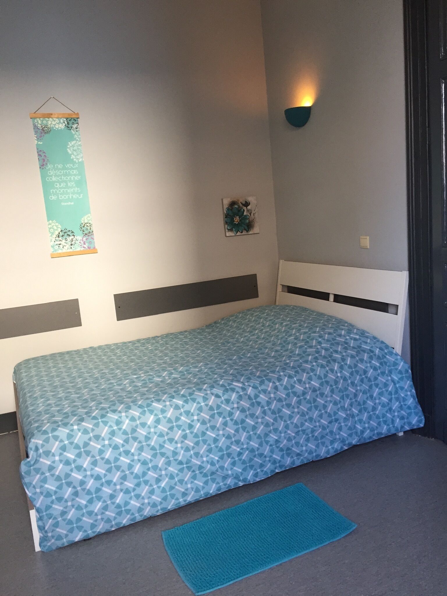 Ein Schlafzimmer mit einem Bett, einer Wandleuchte, einem dekorativen Gegenstand und einer Wanddekoration.