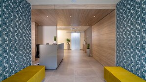 Una moderna zona de recepción con un mostrador central, plantas en macetas y un techo de madera.