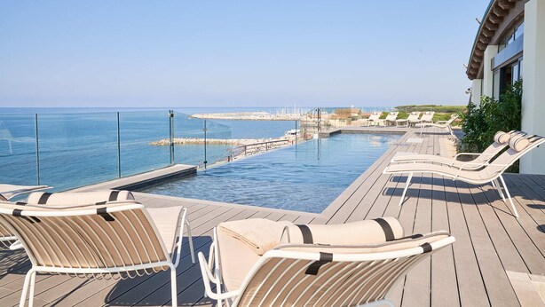 Un área junto a la piscina con sillas de descanso y vistas al mar.