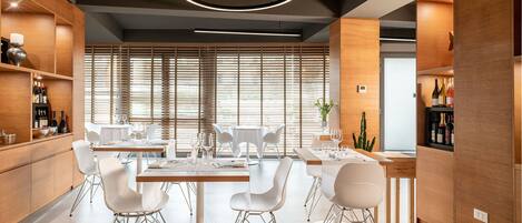 Un comedor moderno con paneles de madera, sillas blancas e iluminación colgante.
