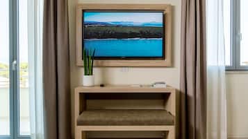 A television mounted on a wall with a view of a landscape, a small table with a plant, and a bench.