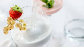 Ein Glas Milch mit Erdbeere und Trauben daneben.