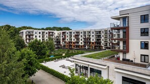 A modern apartment complex with multiple balconies, a rooftop garden, and a well-maintained lawn area. - Apartamenty Sun&Snow Polanki Park (Kolobrzeg)