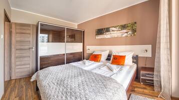 A bedroom with a large bed, a wardrobe, a painting on the wall, and a wooden floor.