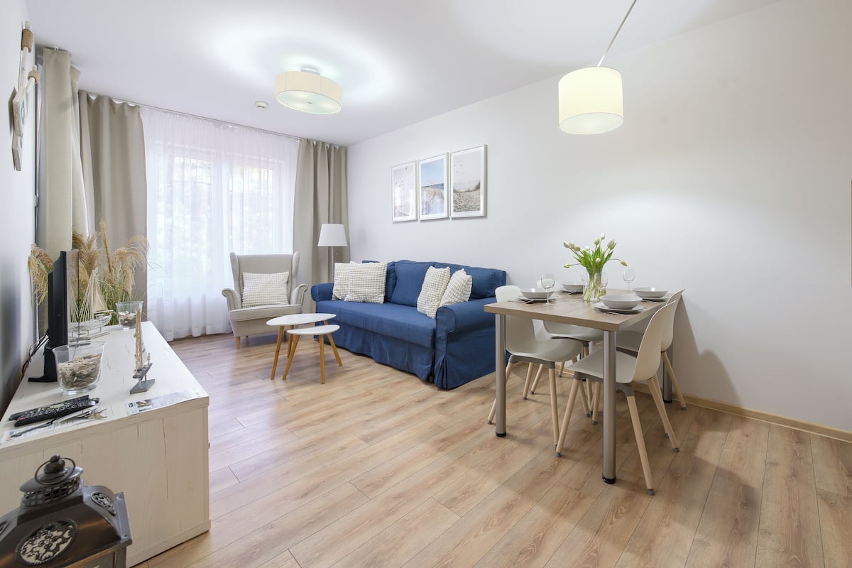 A modern living room with a sofa, dining table, and kitchen area.