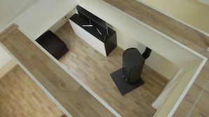 Une pièce moderne et compacte, dotée d’un plancher en bois, d’un canapé noir, d’une petite table et d’une poubelle noire.