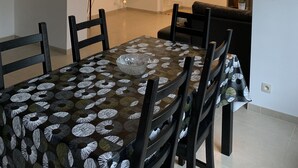 A dining area with a table set for four, a staircase leading to an upper level, and a hanging light fixture. - Petit Coin De Paradis (Charleroi)