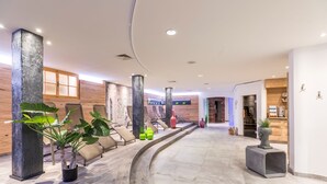 A modern lobby with a curved floor, large pillars, and seating areas. - Hotel Flachauerhof  (Flachau)