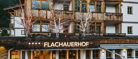 Un immeuble à plusieurs étages doté d’une façade en bois, de balcons et d’une enseigne indiquant « FLACHAUERHOF ».