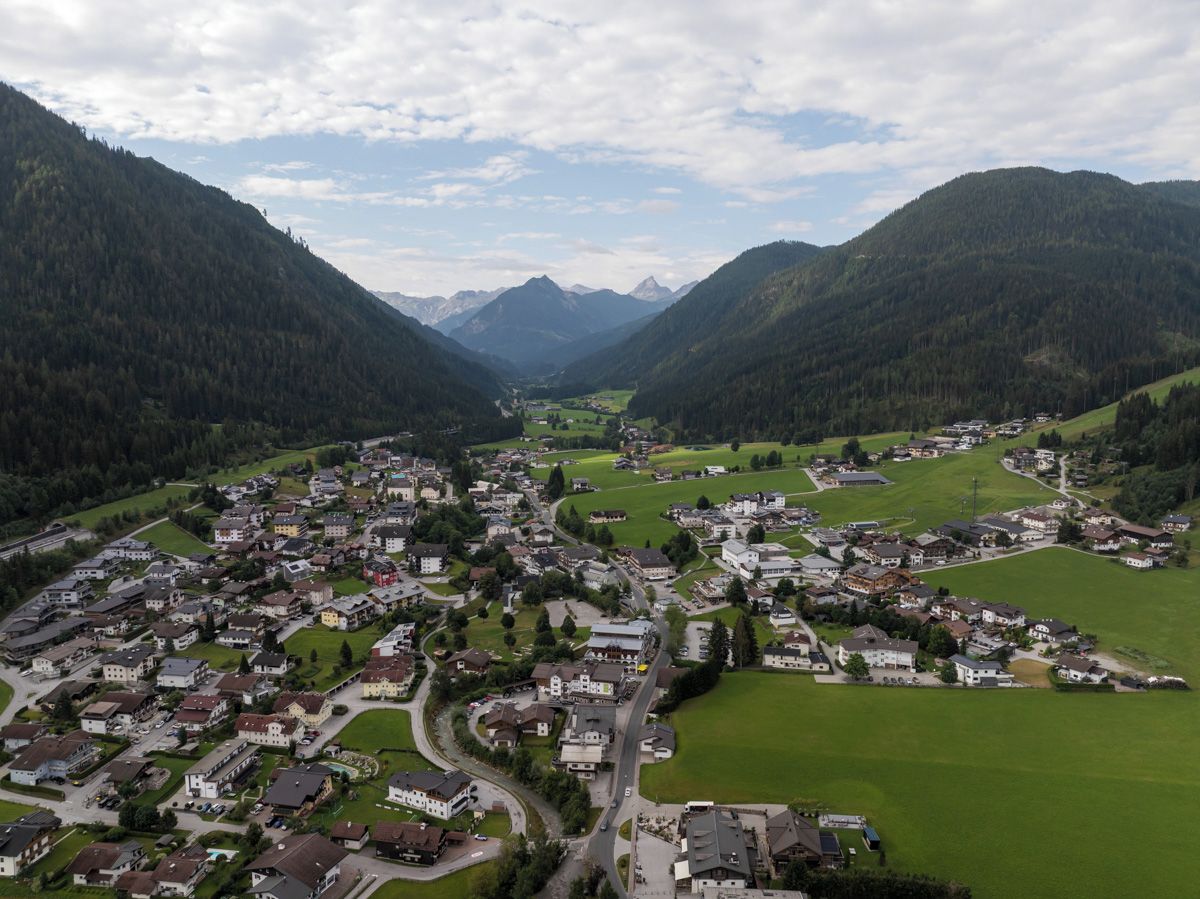 Eine Stadt liegt eingebettet in ein Tal, mit einer kurvenreichen Straße und Häusern.