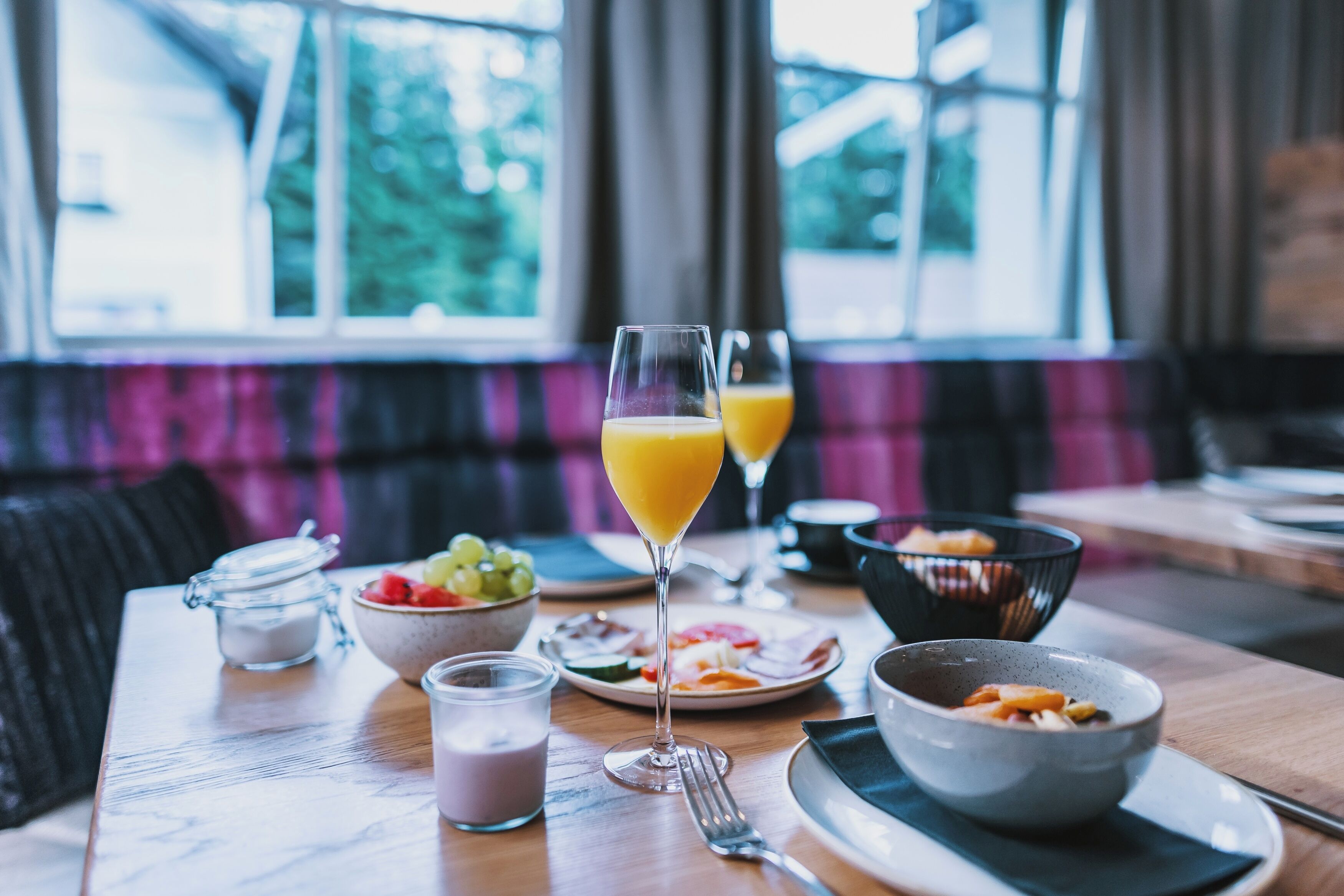 Una escena de desayuno con una mesa, platos, vasos y cuencos llenos de comida.