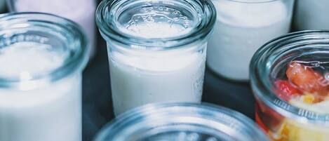 A variety of small glass jars containing different food items, likely dairy products or desserts, arranged on a surface.