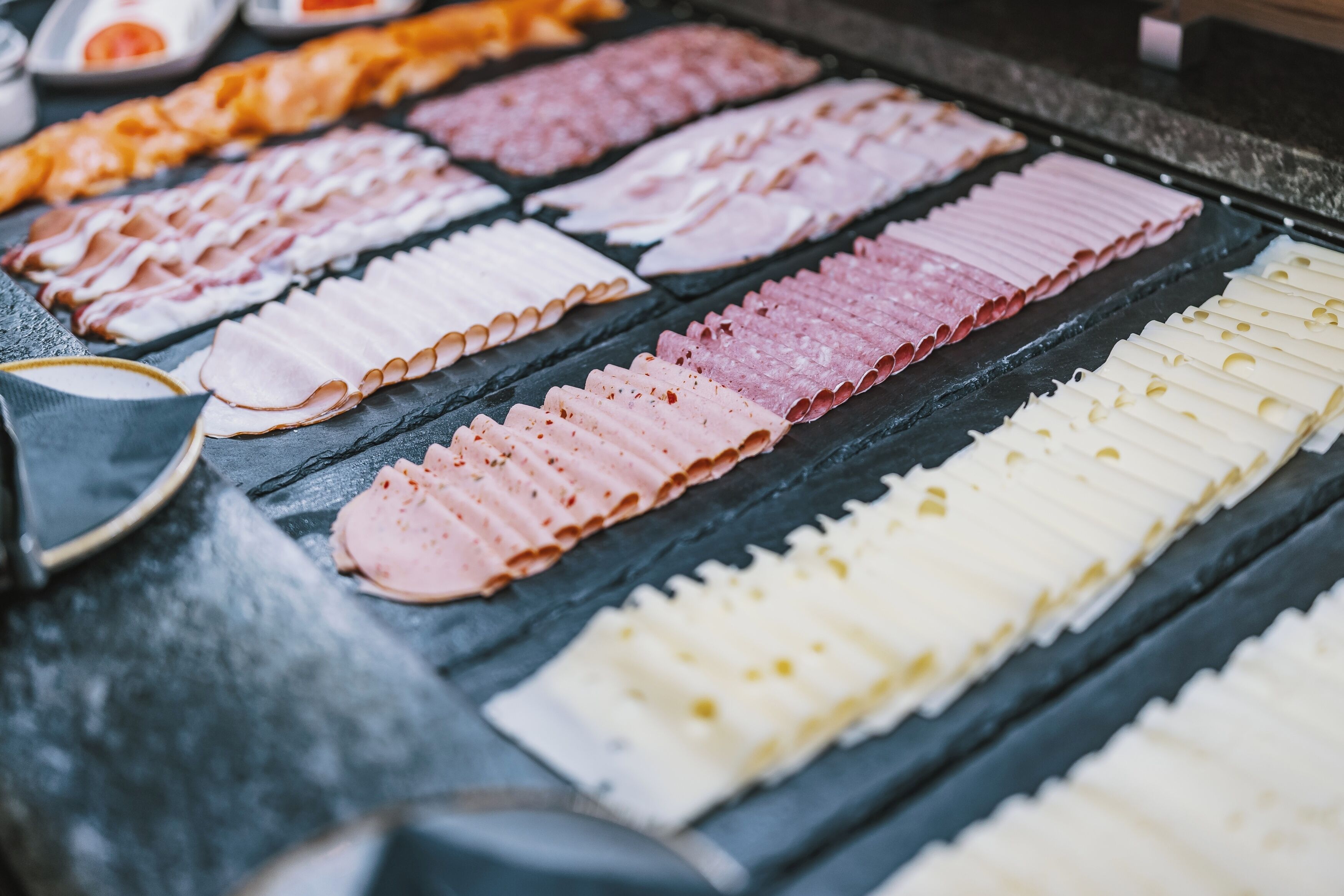 Diversas fatias de carne sobre uma base de ardósia preta.