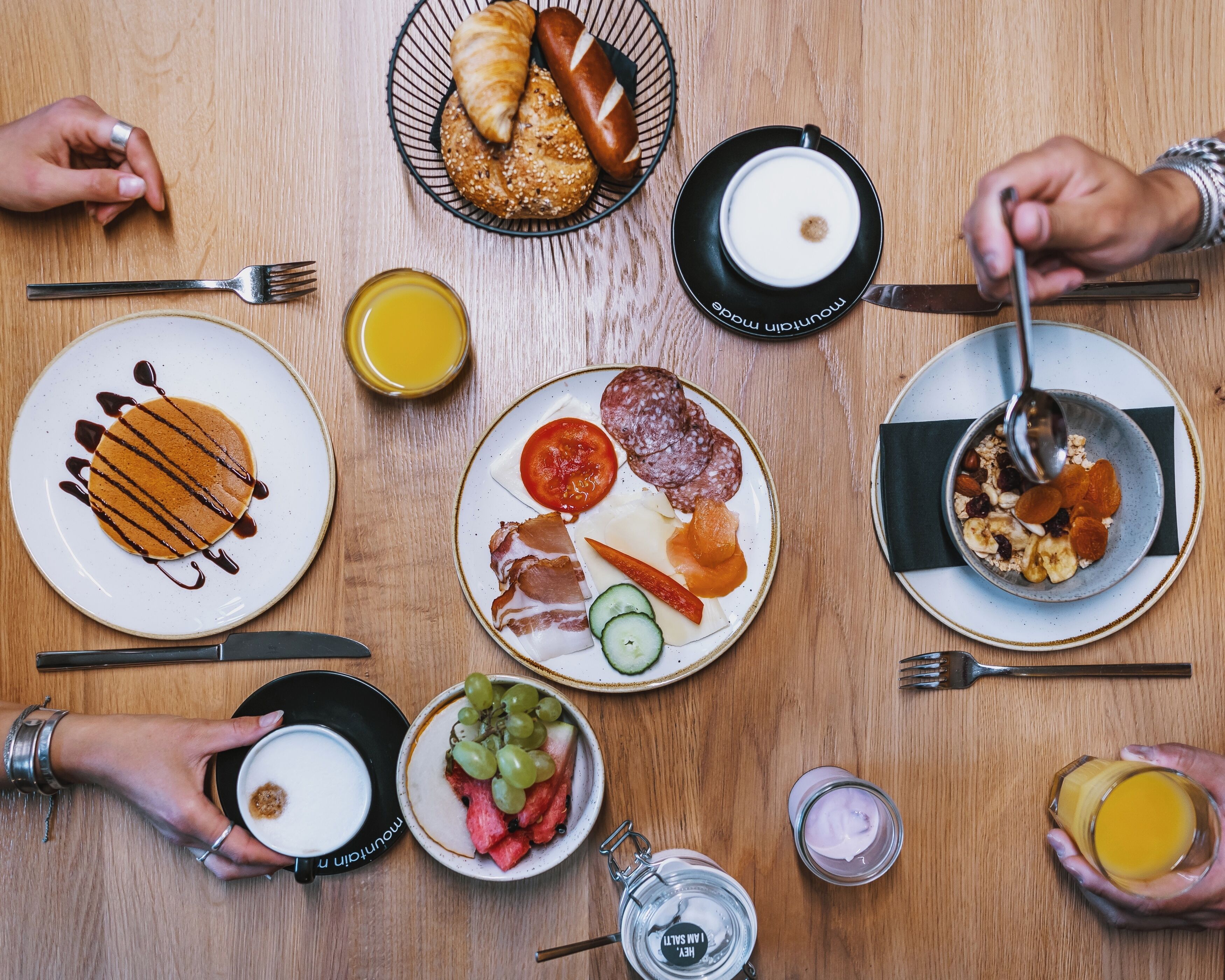 A breakfast setting with various food items and drinks on a wooden table.
