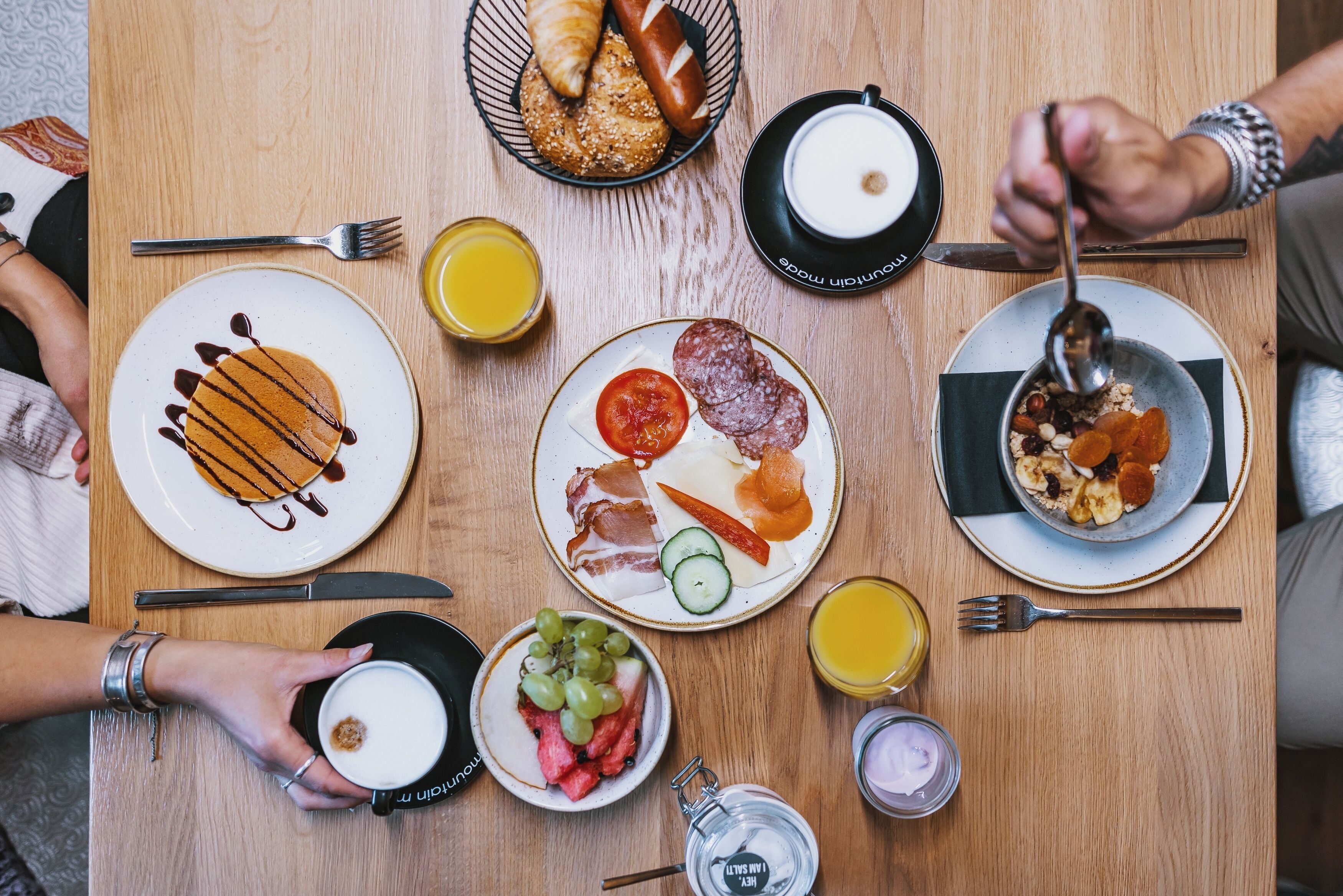 A breakfast setting with various food items and drinks on a wooden table.