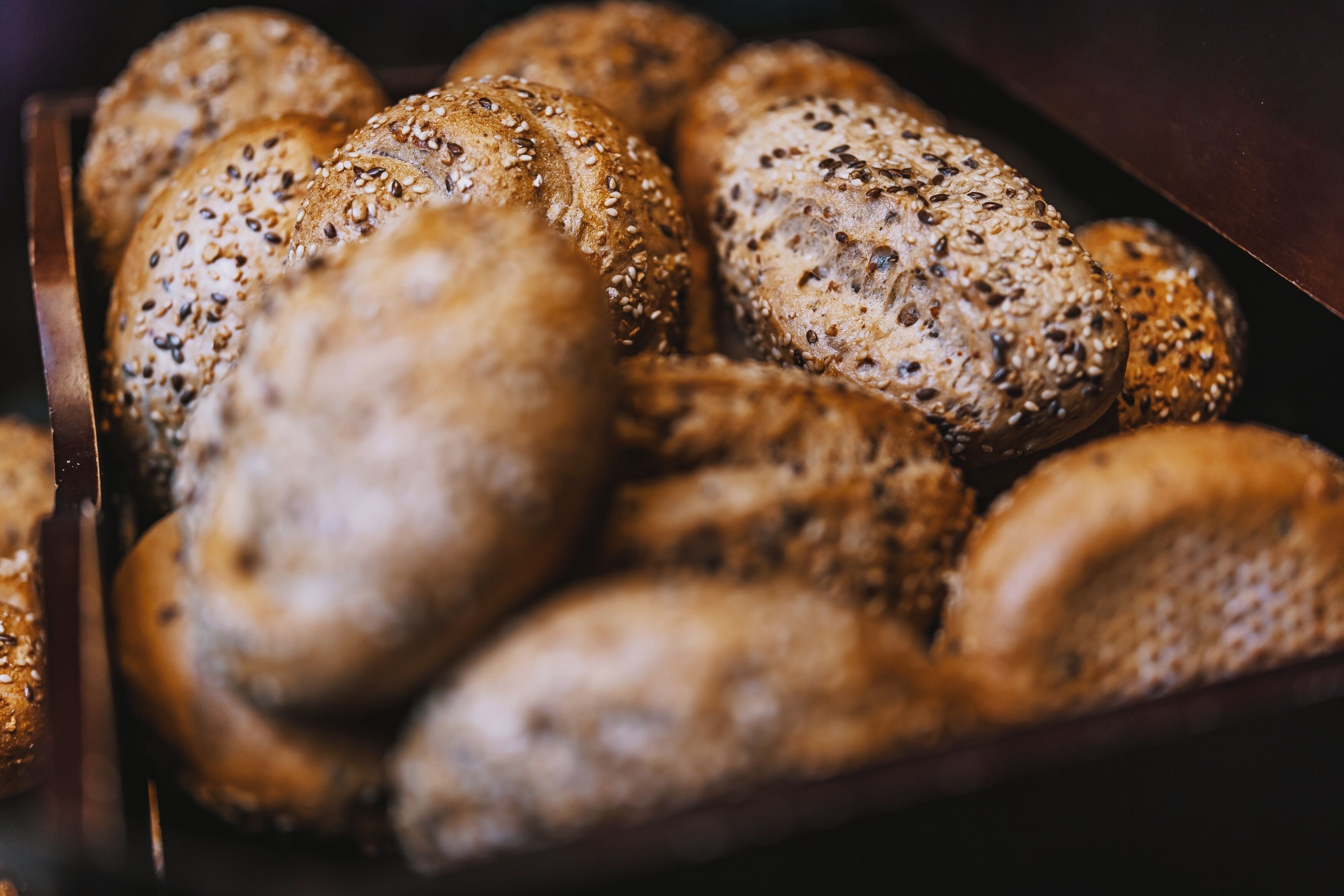 A tray of various types of bread, including whole grain and seeded varieties.