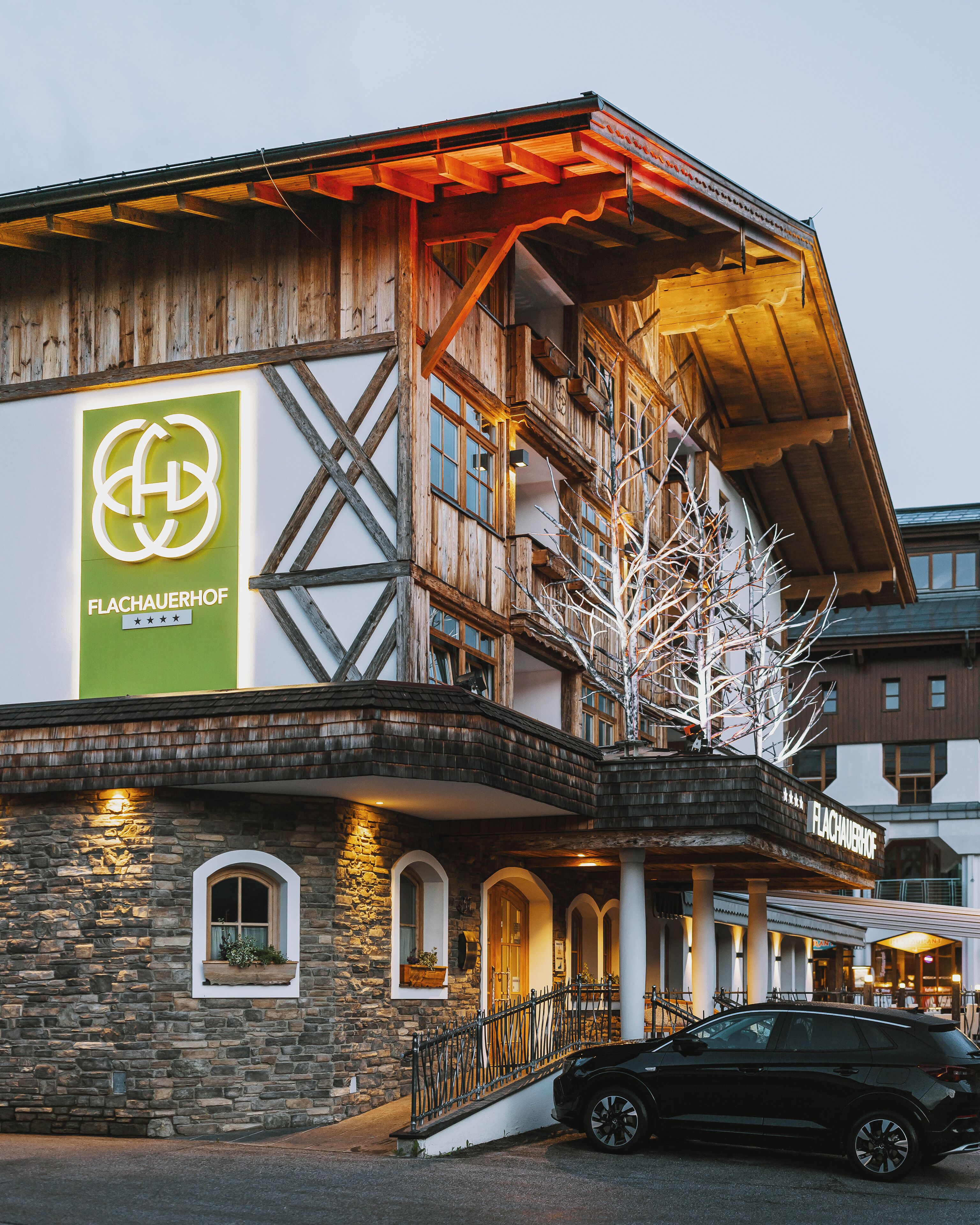 A hotel with a wooden facade, stone lower section, and a sign with a logo and name.