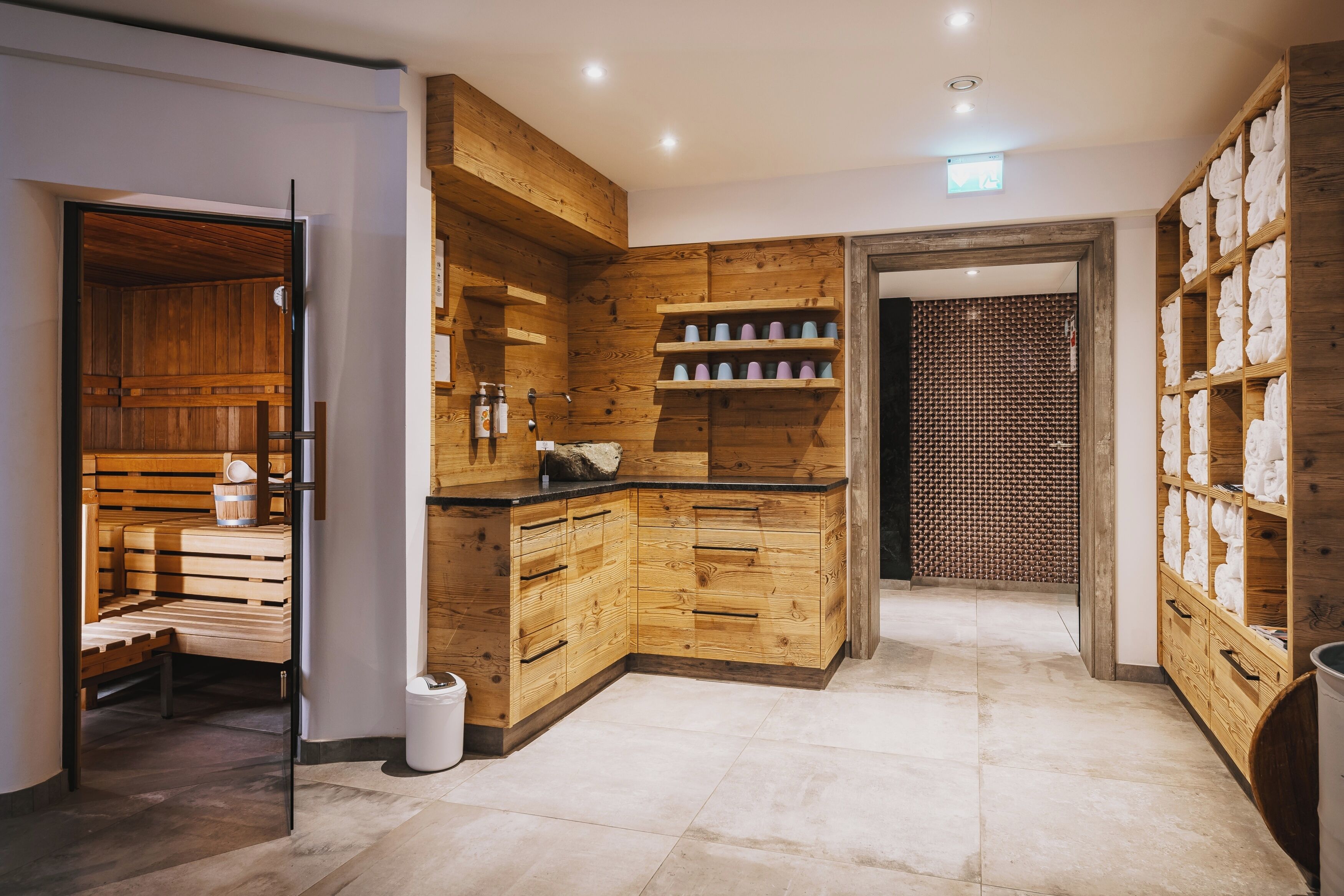 A modern kitchen with wooden cabinetry, a built-in bench, and a tiled floor.