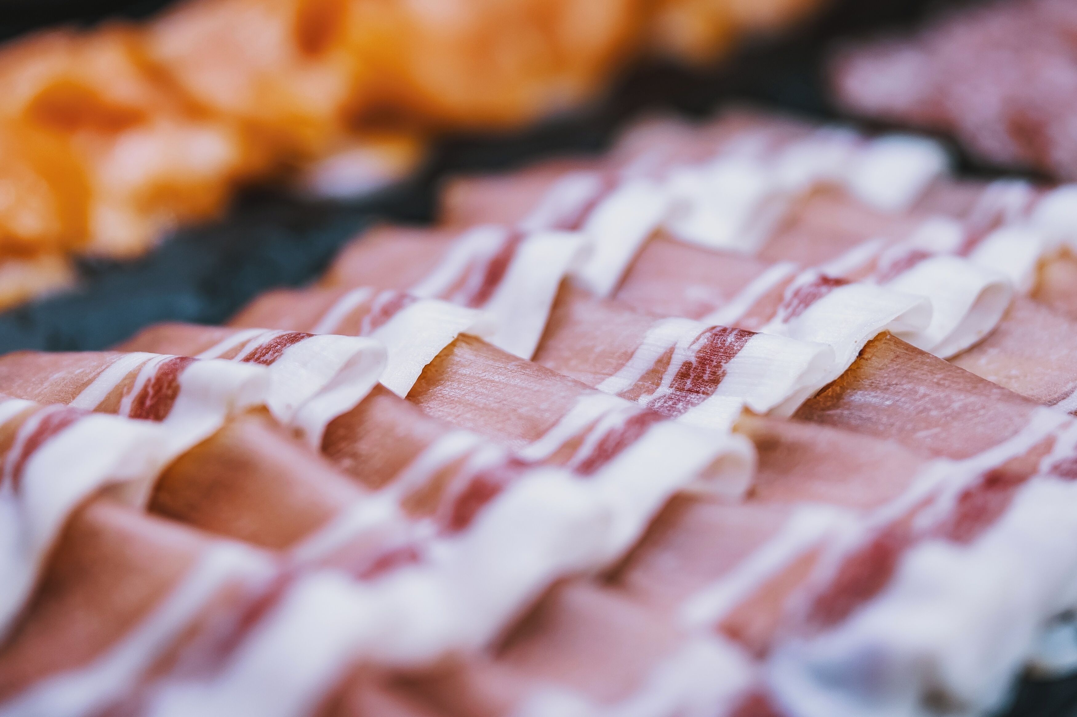 A close-up of sliced meat with white sauce drizzled on top.