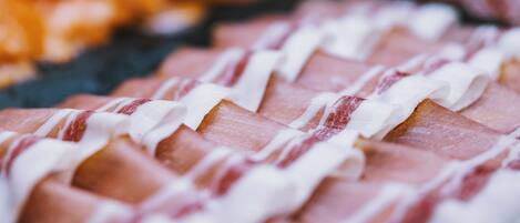 A close-up of sliced meat with white sauce drizzled on top.