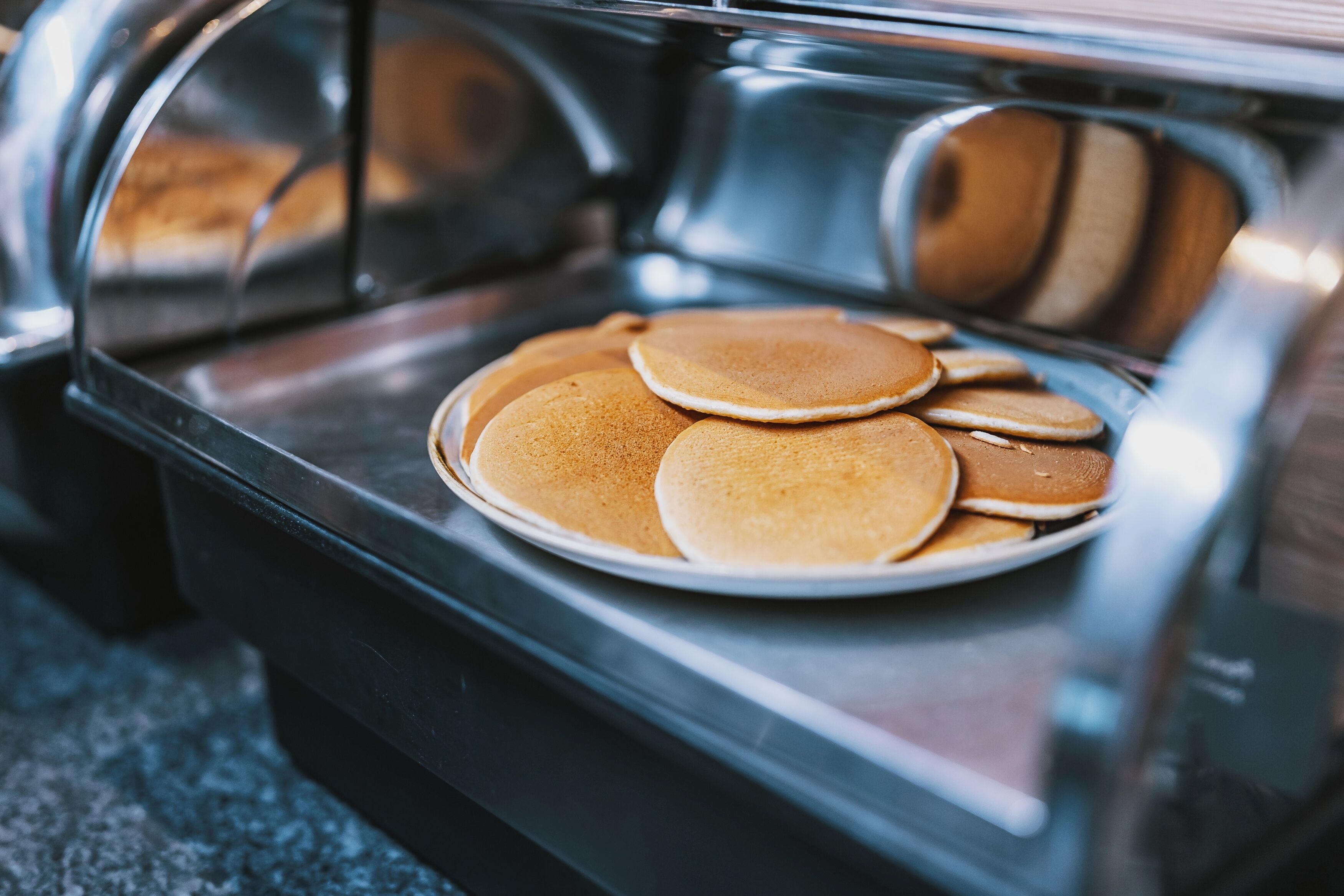 A buffet counter with a plate of pancakes.