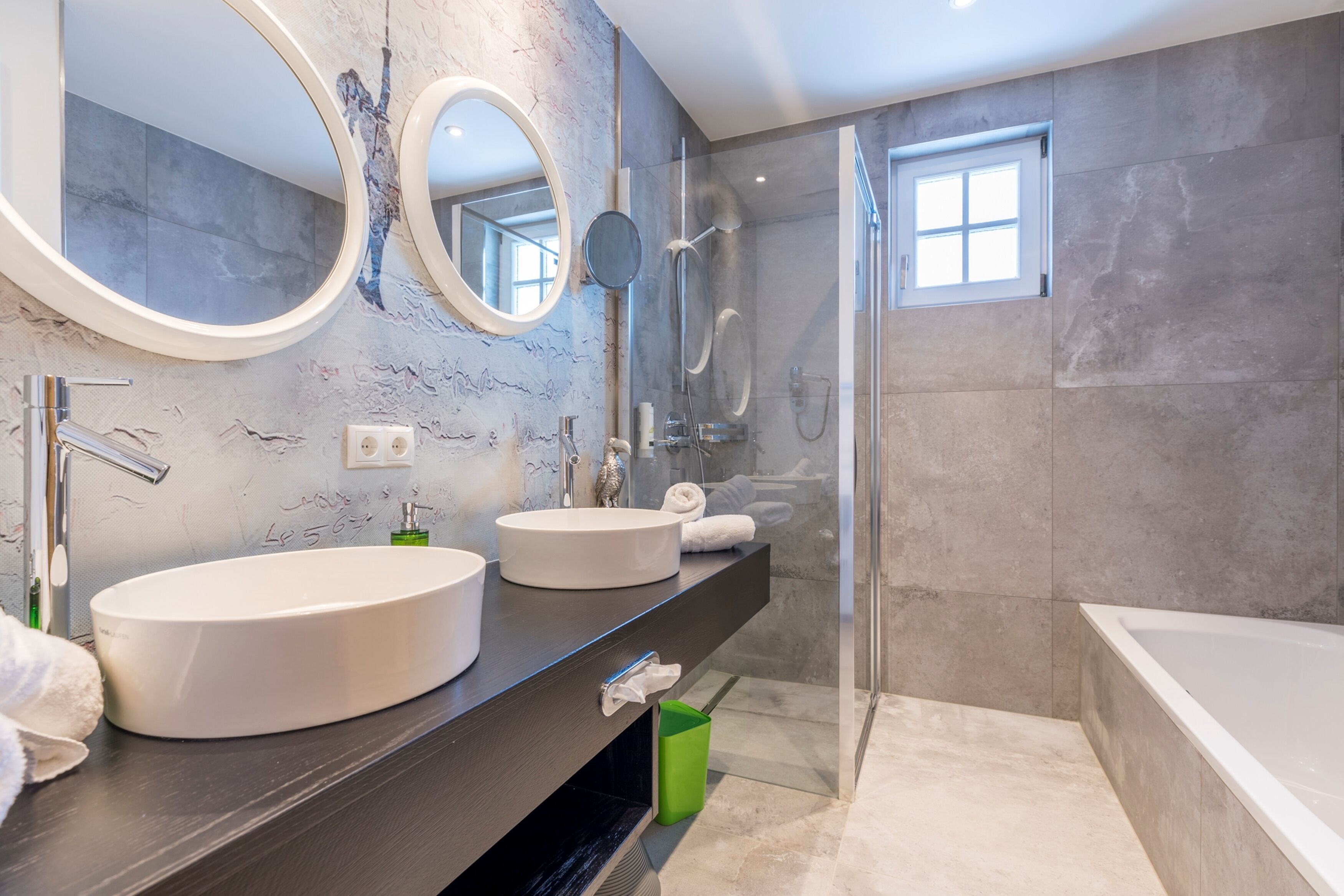 Une salle de bain moderne avec deux vasques rondes, un grand miroir et une douche à l’italienne.